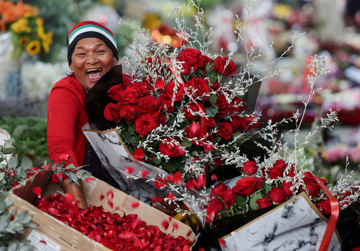 Một người bán hàng tạo dáng chụp ảnh tại chợ hoa phố Adderley vào Ngày lễ tình nhân ở Cape Town, Nam Phi, ngày 14-2 - Ảnh: REUTERS