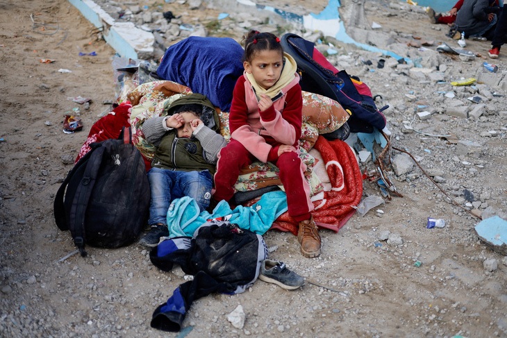 Những đứa trẻ ngồi nghỉ bên đường sau khi được sơ tán khỏi Bệnh viện Nasser ở thành phố Khan Younis hôm 15-2 - Ảnh: REUTERS
