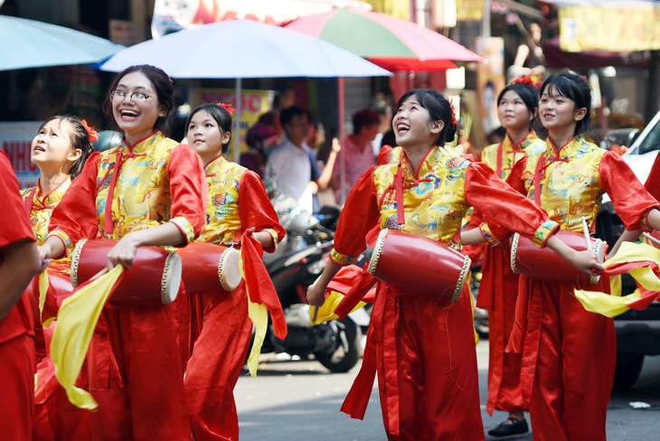 Các cô gái trong trang phục truyền thống đầy màu sắc vui tươi biểu diễn tiết mục múa trên đường diễu hành