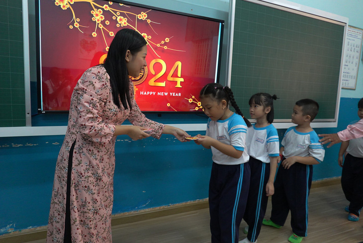 Giáo viên Trường tiểu học Trần Hưng Đạo, quận 1, lì xì cho học sinh và chúc Tết các em - Ảnh: NHƯ HÙNG