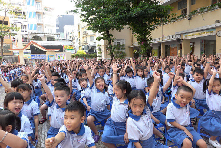 Học sinh Trường tiểu học Trần Hưng Đạo, quận 1, TP.HCM giơ tay thể hiện sự quyết tâm sẽ học thật tốt trong ngày đầu tiên đi học lại sau Tết - Ảnh: NHƯ HÙNG