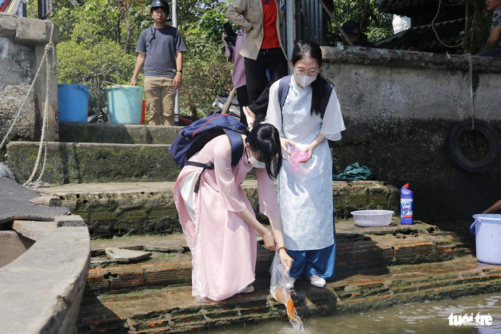 Hai thiếu nữ tiến hành thả cá chép sau khi làm lễ xong tại chùa Diệu Pháp - Ảnh: TIẾN QUỐC