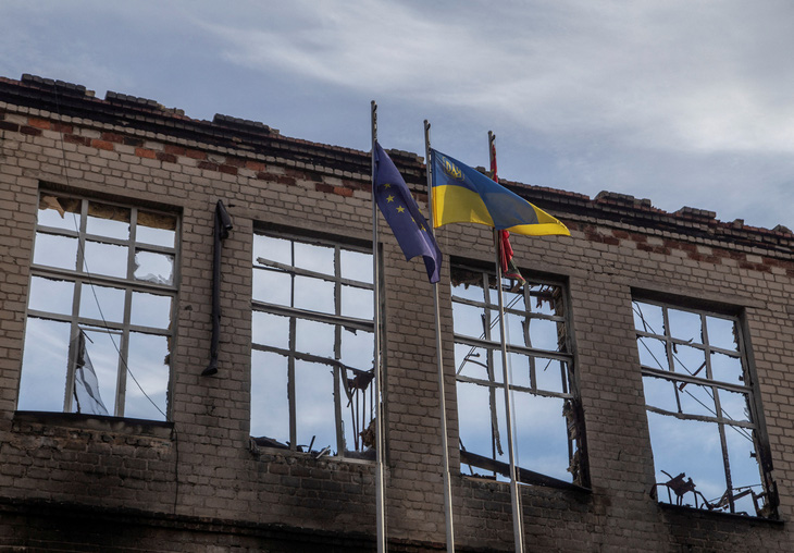 Quốc kỳ Ukraine và cờ Liên minh châu Âu tung bay tại một ngôi trường bị phá hủy bởi pháo kích của Nga ở Avdiivka, vùng Donetsk - Ảnh: REUTERS