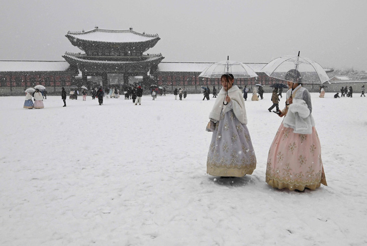 Du khách mặc trang phục hanbok truyền thống đi dạo dưới tuyết tại cung điện Kyungbokgung ở trung tâm Seoul - Ảnh: Jung Yeon-je/AFP