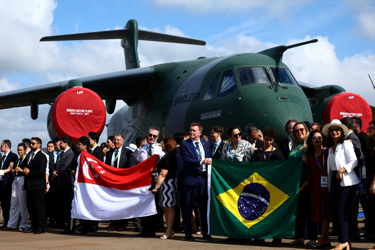 Phái đoàn Brazil chụp ảnh bên cạnh máy bay Embraer C-390 Millennium (Brazil) tại Triển lãm hàng không Singapore ngày 20-2 - Ảnh: REUTERS