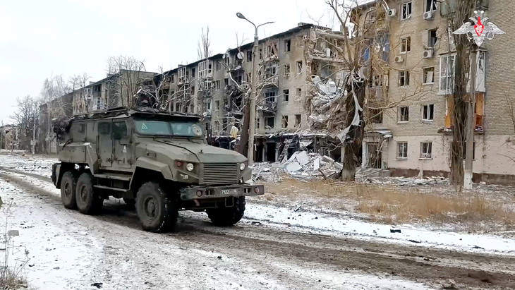 Một chiếc xe quân sự của Nga đi qua khu vực có các tòa nhà đã bị phá hủy trong xung đột tại thị trấn Avdiivka vào ngày 20-2 - Ảnh: REUTERS