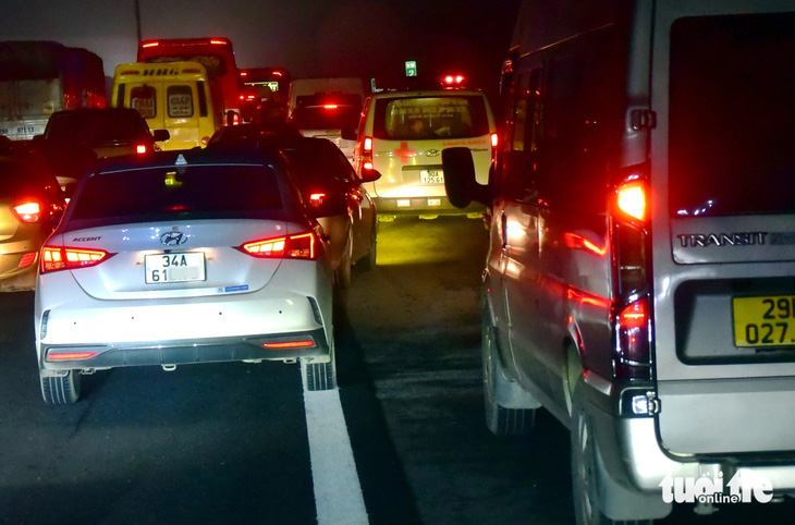 Xe cấp cứu bị kẹt giữa những chiếc xe lấn làn khẩn cấp (khi xe ùn tắc do một tai nạn nhỏ) trên cao tốc Pháp Vân - Cầu Giẽ. Ảnh chụp tại địa phận huyện Duy Tiên (tỉnh Hà Nam) hướng vào TP Hà Nội tối 6-2 - Ảnh: T.T.D.