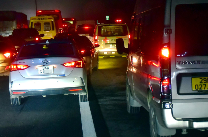 Xe cấp cứu bị kẹt giữa những chiếc xe lấn làn khẩn cấp (khi xe ùn tắc do một tai nạn nhỏ) trên cao tốc Pháp Vân - Cầu Giẽ. Ảnh chụp tại địa phận huyện Duy Tiên (tỉnh Hà Nam) hướng vào TP Hà Nội tối 6-2 - Ảnh: T.T.D.
