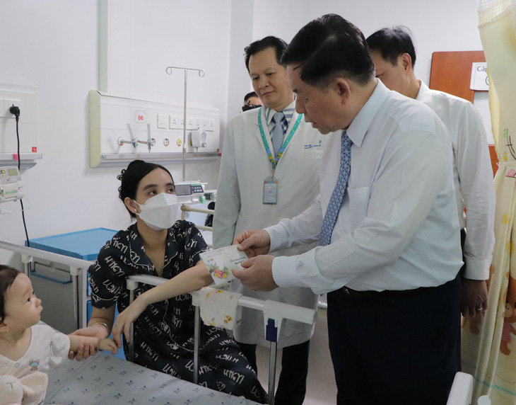 Ông Nguyễn Trọng Nghĩa thăm hỏi và tặng quà động viên cho gia đình bệnh nhi đang điều trị tại bệnh viện - Ảnh: CẨM NƯƠNG
