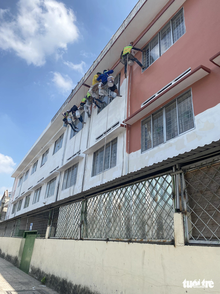 Đội ngũ thi công đang sơn sữa bên ngoài Trường tiểu học Trần Văn Vân - Ảnh: NGỌC PHƯỢNG