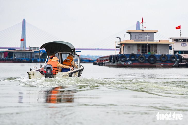 Cảnh sát tiếp cận một tàu chở hàng trên sông Hồng - Ảnh: HỒNG QUANG