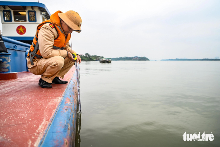 Cảnh sát kiểm tra vạch dấu mớn nước của tàu chở hàng trên sông Hồng - Ảnh: HỒNG QUANG