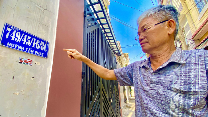 Ông Lê Tấn Lâm chỉ tay biển số nhà có 4 xuyệt tại Huỳnh Tấn Phát (quận 7, TP.HCM) - Ảnh: TIẾN QUỐC