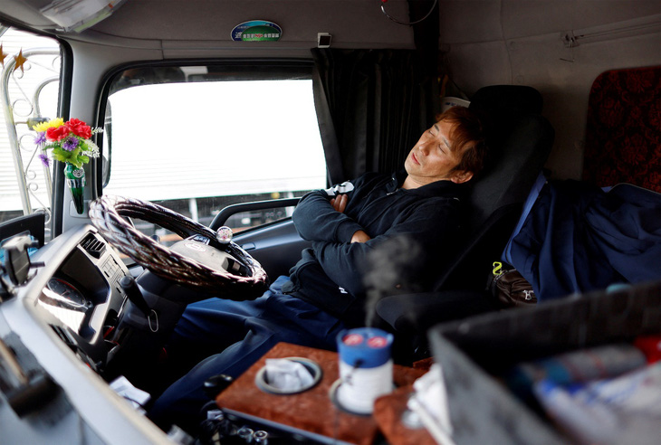 Tài xế xe tải Yuichi Tomita, 39 tuổi, nghỉ ngơi bên trong chiếc xe tải 10 tấn của mình tại khu vực đỗ xe dọc đường cao tốc ở Chiba, phía đông Tokyo, Nhật Bản ngày 6-4-2023. Ảnh: reuters.com