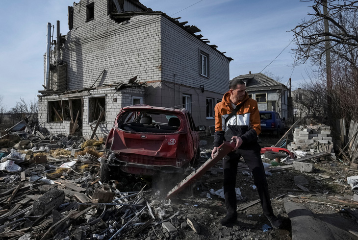 Người dân địa phương chuẩn bị kéo chiếc xe hơi hỏng đến gần một tòa nhà dân cư bị hư hại trong bối cảnh Nga tấn công thành phố Dnipro, Ukraine, ngày 26-2 - Ảnh: REUTERS