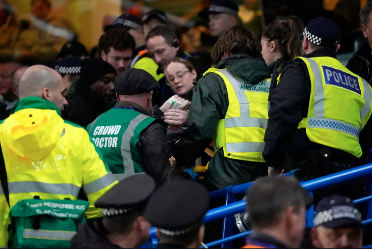 Nhân viên sân Stamford Bridge cố gắng tiếp cận cổ động viên gặp nạn của Leeds - Ảnh: AP