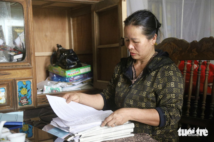 Bà Nguyễn Thị Mai (vợ ông Hàn Đức Long) xem lại những lá đơn bà từng viết để gửi đến các cơ quan chức năng, kêu oan cho chồng - Ảnh: DANH TRỌNG