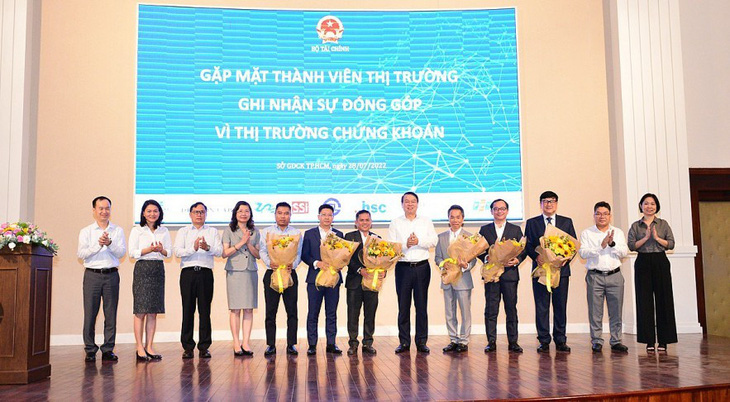 Thứ trưởng Nguyễn Đức Chi (thứ 6 từ trái sang) tặng hoa cảm ơn các thành viên thị trường ngày 28-7-2022 - Ảnh: HDB