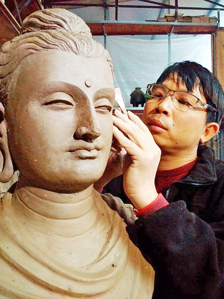 Nghệ sĩ điêu khắc Lương Thanh bên bức tượng Phật tại xưởng điêu khắc của anh - Ảnh: T.ĐIỂU