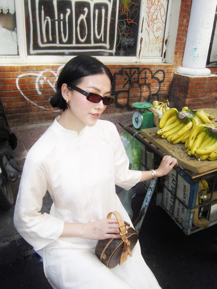 Ở mẫu áo dài màu trắng ngà nhẹ nhàng, Phương Khánh khéo léo kết hợp mắt kính màu đen, túi xách hàng hiệu chuẩn dáng quý cô sành điệu.