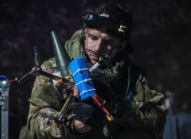 Một quân nhân Ukraine gắn đạn pháo vào một FPV drone, ảnh ngày 4-2-2023 - Ảnh: REUTERS