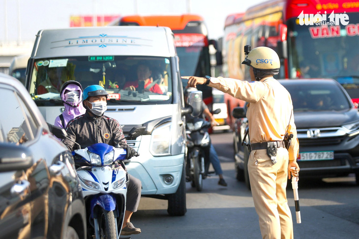 Cảnh sát giao thông túc trực tại các giao lộ để hướng dẫn người dân đi lại trên quốc lộ 1 đoạn qua huyện Bình Chánh (TP.HCM) vào sáng 4-2 - Ảnh: PHƯƠNG QUYÊN