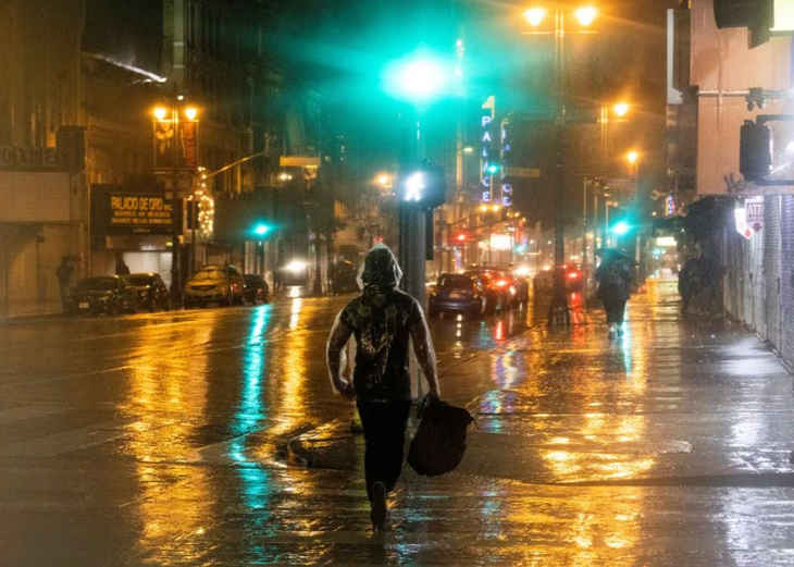 Người dân chật vật di chuyển dưới cơn mưa nặng hạt và dai dẳng vào tối ngày 4-2 - Ảnh: REUTERS