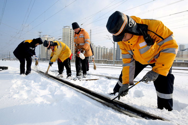 Các nhân viên dọn tuyết trên đường ray dọc theo ga đường sắt Đông Liên Vân Cảng, tỉnh Giang Tô, miền đông Trung Quốc ngày 5-2 - Ảnh: REUTERS