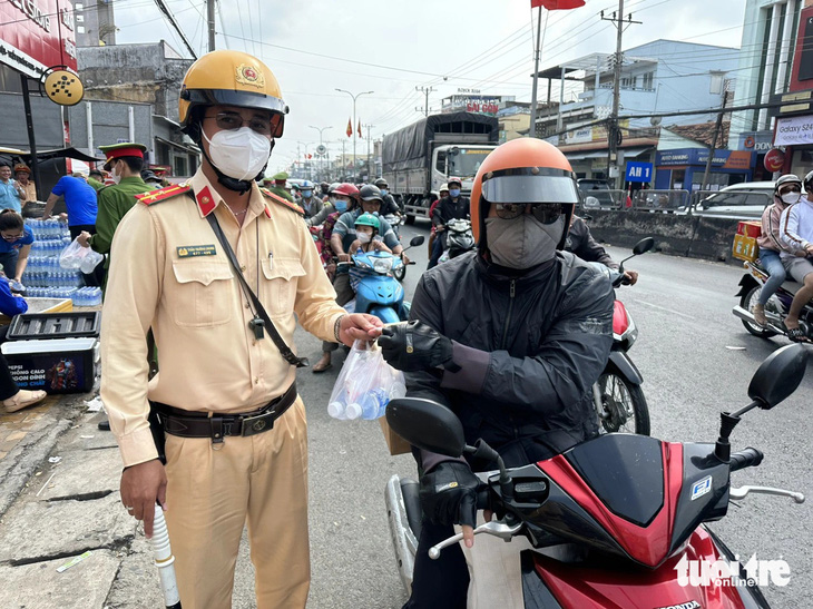 Cảnh sát giao thông phát nước suối miễn phí cho người dân về quê ăn Tết - Ảnh: HOÀI THƯƠNG