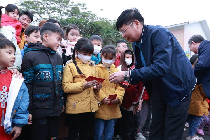 Phó chủ tịch Tổng liên đoàn Lao động Việt Nam Phan Văn Anh lì xì các cháu nhỏ trước khi xe chở công nhân và gia đình xuất hành về quê ăn Tết - Ảnh: HÀ QUÂN