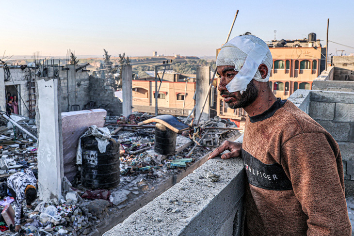 Người đàn ông bị thương ở đầu đứng nhìn đống đổ nát của những tòa nhà sau khi Israel ném bom ở thành phố Rafah, phía nam Dải Gaza, ngày 7-2 - Ảnh: AFP