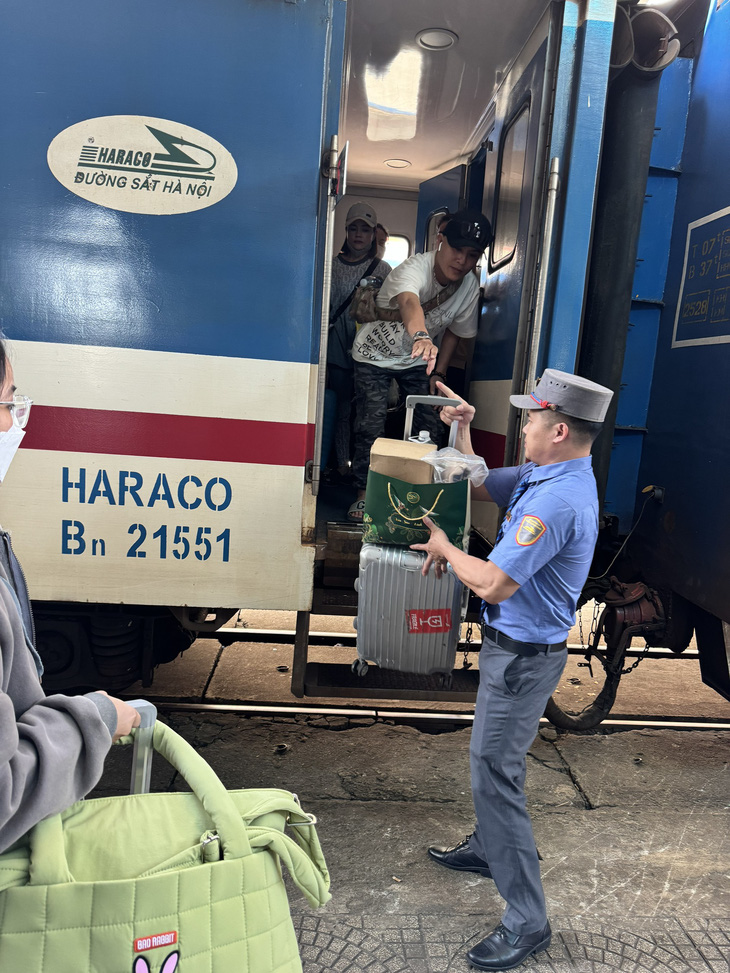 Nhân viên tàu SE6 hỗ trợ hành khách xuống ga Đà Nẵng ngày 6-2 - Ảnh: CÔNG DŨNG 