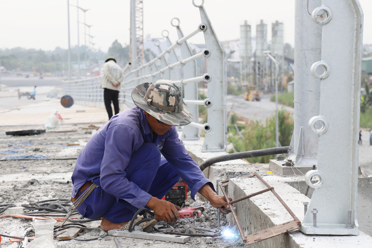 Công nhân đang thi công những hạng mục phụ của cầu Trần Hoàng Na trong những ngày giáp Tết - Ảnh: CHÍ QUỐC