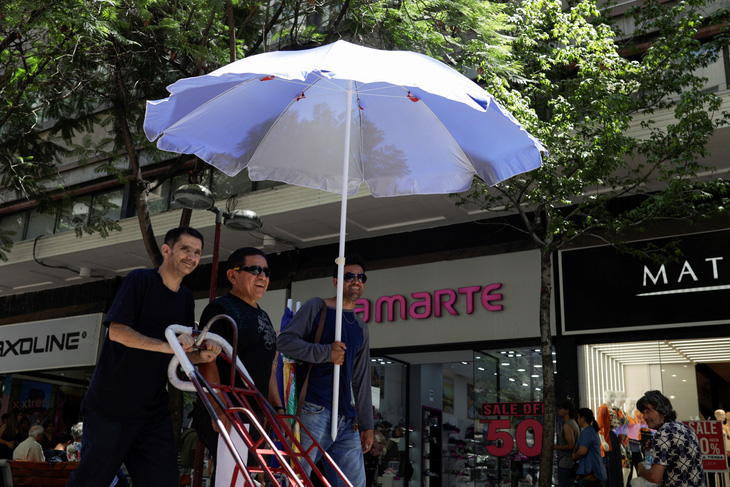Những người đàn ông dùng ô che chắn trong đợt nắng nóng tại Santiago, Chile vào ngày 31-1-2024 - Ảnh: REUTERS