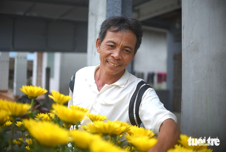 Ông Phan Văn Ta - ba của bé Ca - vui vẻ khoe chậu hoa cúc của gia đình đón Tết năm nay - Ảnh: LÂM THIÊN