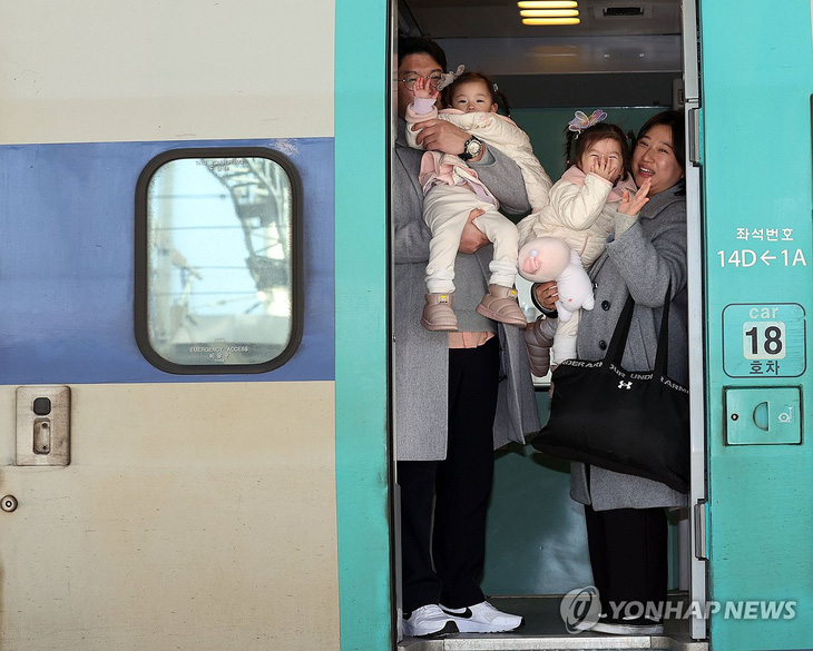Một cặp song sinh vẫy tay với ống kính khi vừa lên tàu ở nhà ga Seoul để về quê ăn Tết - Ảnh: YONHAP