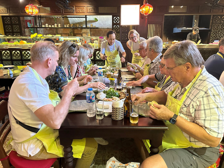 Du khách Pháp trải nghiệm nấu ăn món ăn đặc trưng của Việt Nam trong tour - Ảnh: B.C.