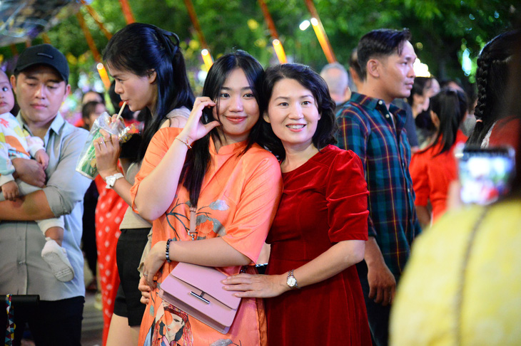 Các bạn trẻ xúng xính áo dài hào hứng chụp ảnh check-in tại đường hoa Nguyễn Huệ - Ảnh: HẢI QUỲNH