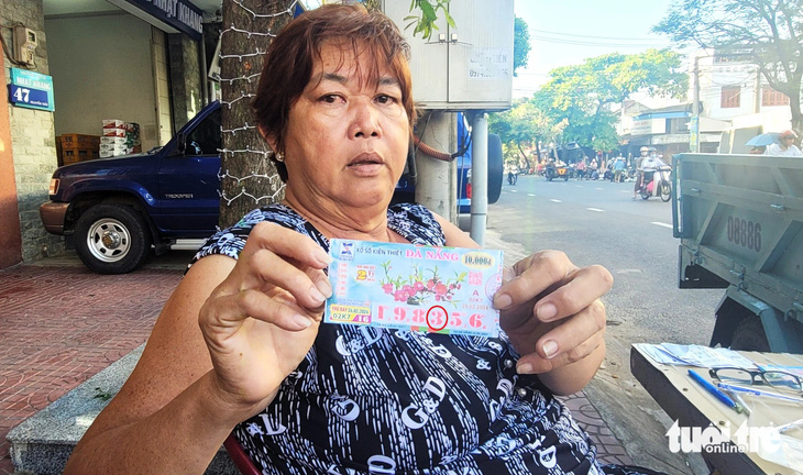 Bà Nguyễn Thị Nguyệt (59 tuổi) cầm trên tay tờ vé số bị cắt dán từ số 0 thành số 3 - Ảnh: NGUYỄN HOÀNG