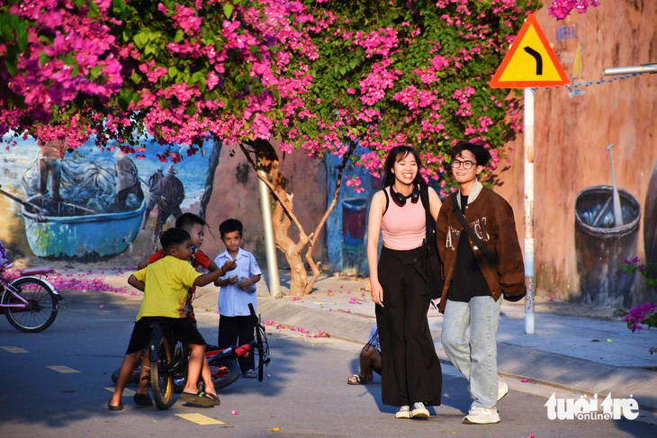 Du khách thích thú check-in tại đường bích họa phủ đầy hoa giấy ở TP Nha Trang - Ảnh: TRẦN HOÀI
