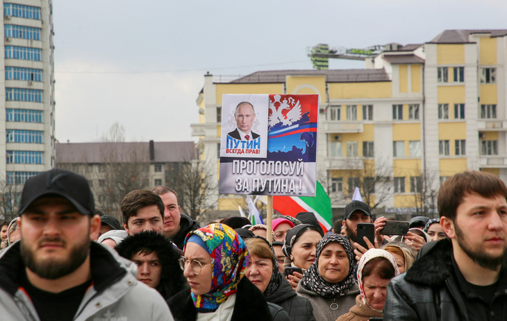 Biểu ngữ ủng hộ Tổng thống Nga Vladimir Putin giữa dòng người ở TP Grozny (Nga) - Ảnh: REUTERS