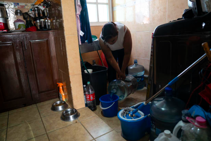 Một phụ nữ đổ nước bình vào xô tại khu chung cư ở Mexico City, Mexico ngày 27-2 năm nay - Ảnh chụp màn hình CBS NEWS/GETTY IMAGES
