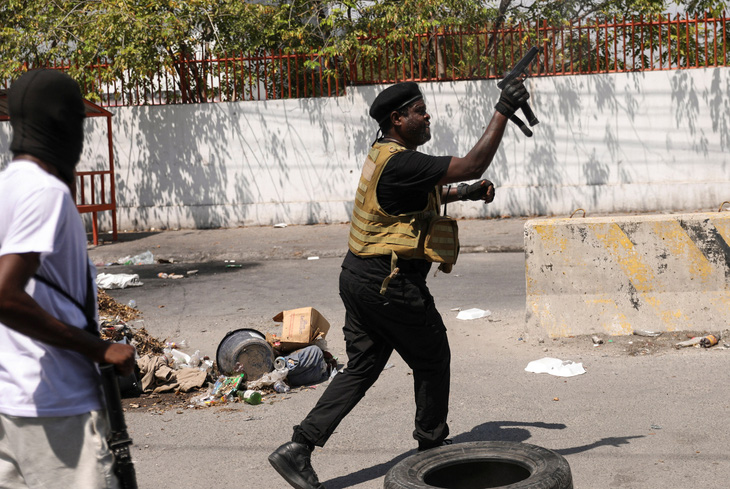 Thủ lĩnh một nhóm vũ trang ở Haiti nổ súng chỉ thiên trên đường phố hôm 11-3 - Ảnh: REUTERS