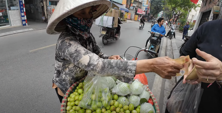 Hình ảnh người phụ nữ lấy tờ 200.000 đồng từ tay du khách nước ngoài cho một túi táo ít ỏi - Ảnh cắt từ clip