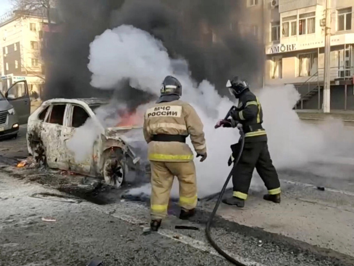 Lính cứu hỏa xử lý ô tô bốc cháy sau cuộc tấn công được cho do Ukraine thực hiện ở Belgorod vào ngày 30-12-2023 - Ảnh: REUTERS