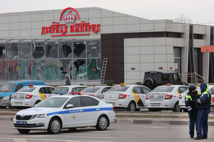 Cảnh sát đứng gác trước một cửa hàng bị hư hại tại hiện trường vụ không kích mới ở Belgorod, Nga hôm 14-3 - Ảnh: AFP