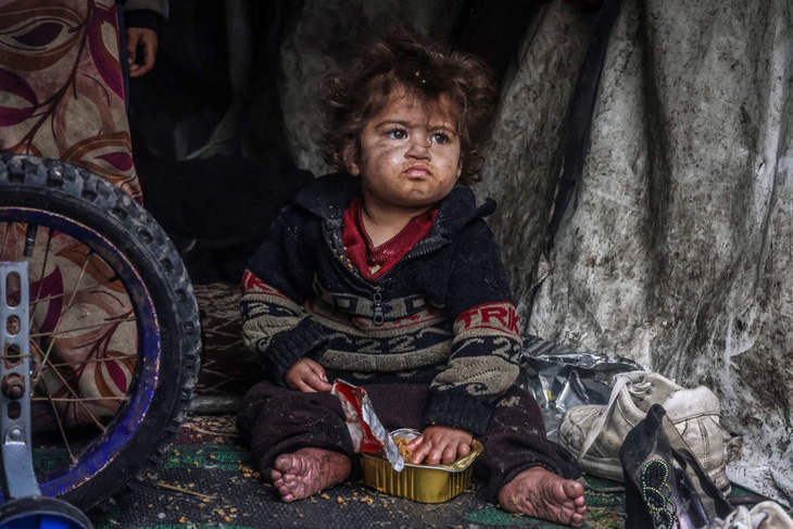 Đứa trẻ Palestine tự bốc thức ăn trong hộp tại một trại lánh nạn tạm thời ở thành phố Rafah, dải Gaza ngày 14-3. Đã có nhiều cảnh báo về nạn đói khi chiến sự ở Gaza đã kéo dài hơn 5 tháng. Ảnh: AFP
