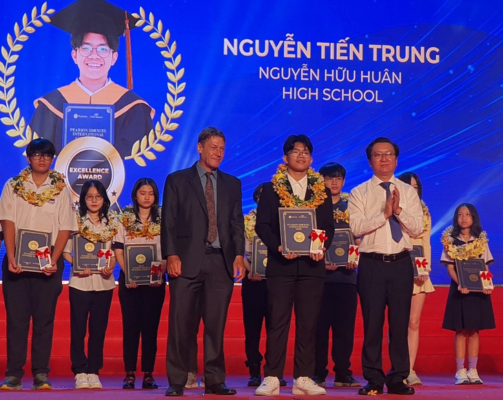 Đại diện EMG Education và ông Nguyễn Bảo Quốc - phó giám đốc Sở GD-ĐT TP.HCM - trao thưởng cho các học sinh - Ảnh: H.HG.