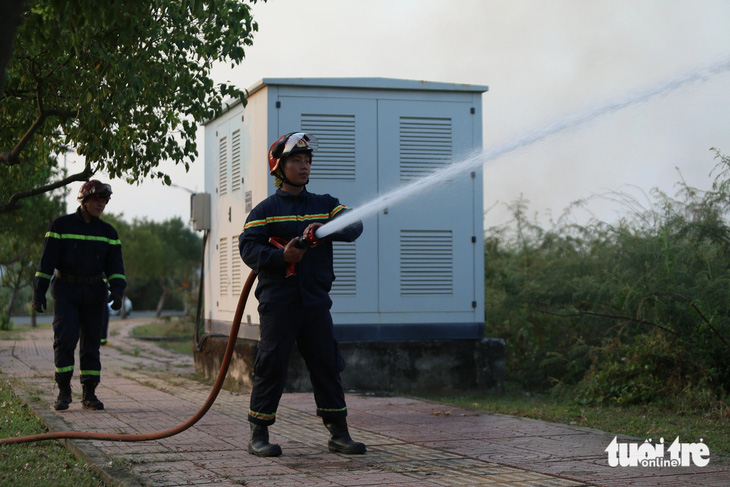 Lực lượng cảnh sát PCCC có mặt phun nước xung quanh tủ điện để tránh lửa bén vào - Ảnh: MINH HÒA