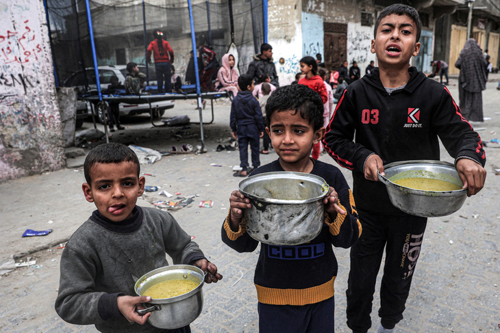 Trẻ em cầm thức ăn từ thiện ở Rafah, phía Nam Gaza, ngày 16-3 - Ảnh: AFP